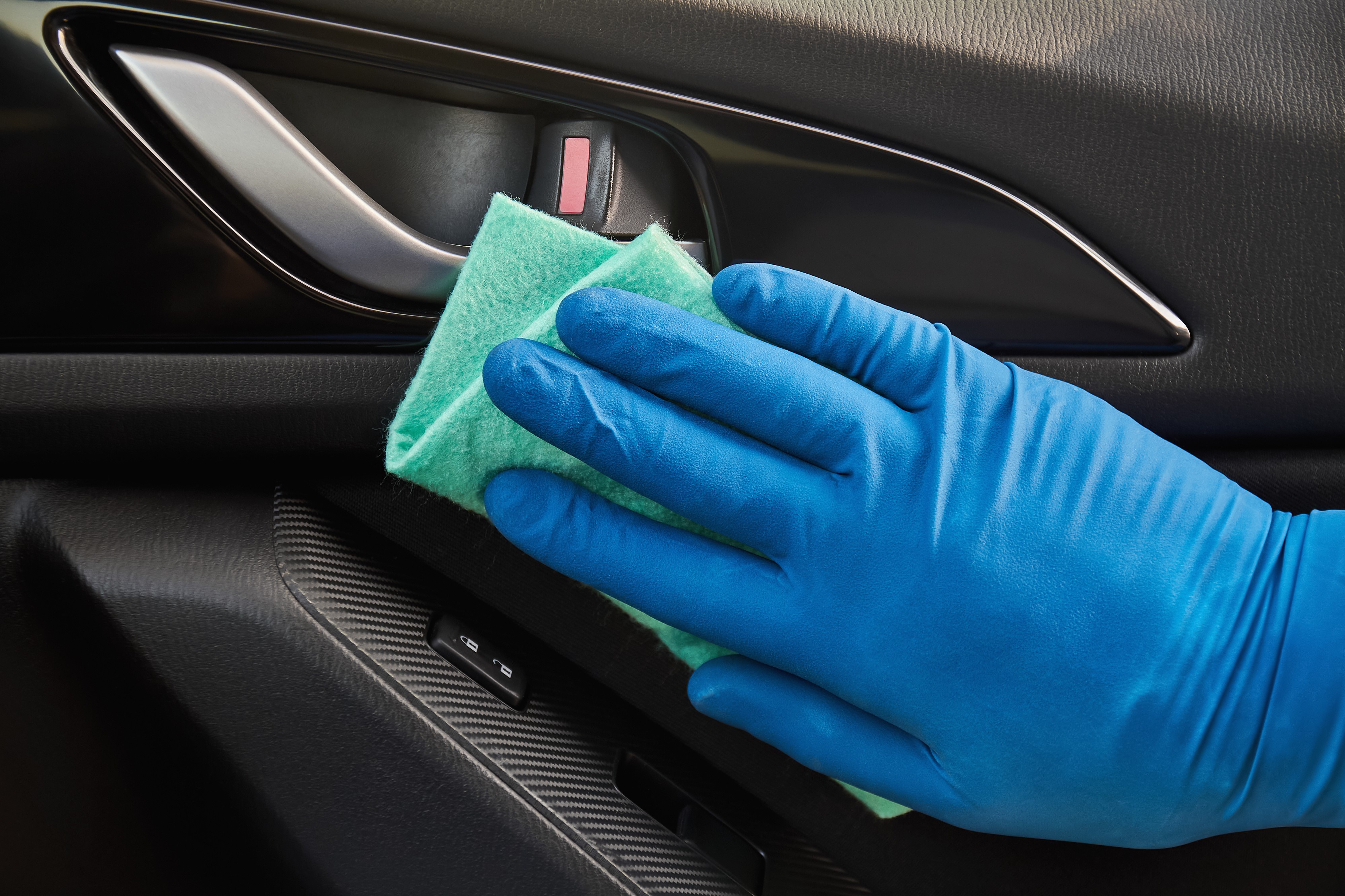 Hand in Glove Cleaning Interior of Car With Microfiber Towel